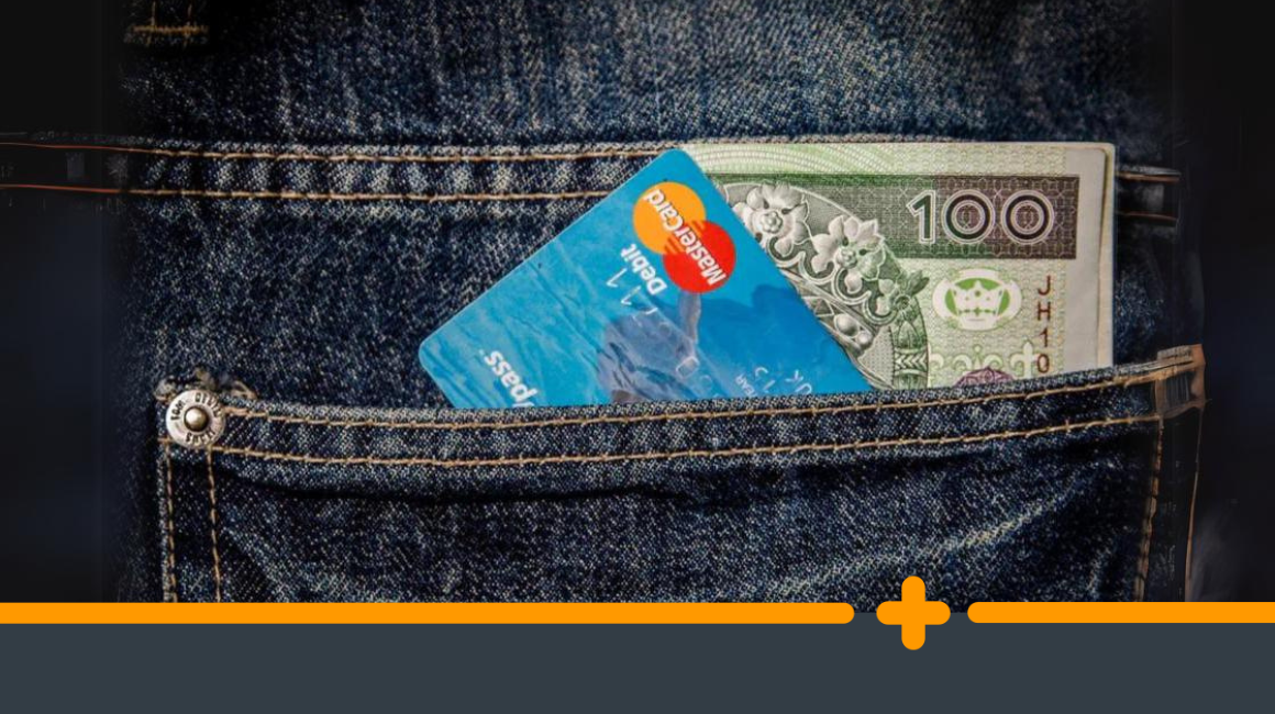 Karta debetowa Mastercard i banknot 100 zł wystające z kieszeni jeansów